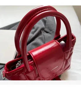 Detail of red quilted faux leather handbag with silver zipper and double top handles