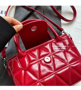Detail view of red quilted bucket bag featuring a strong magnetic closure and glossy finish