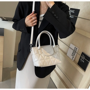 White quilted bucket bag with triangle patterns and top handles shown in a lifestyle setting