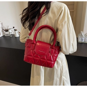 Detailed view of red quilted bucket bag with metallic logo and adjustable strap