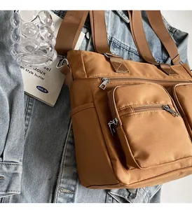 Close-up of brown multi-pocket tote bag with durable zippers and woven shoulder strap