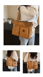 Detail of tan large capacity tote bag featuring dual front zipper pockets and strap