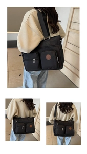 Close-up of black nylon tote bag featuring multi-pocket design and brown leather logo patch