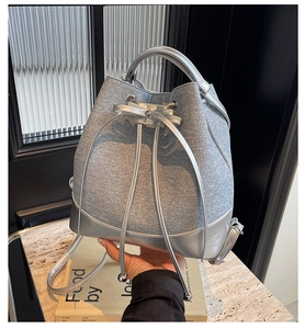 Detail of silver drawstring bucket bag with metallic woven texture and leather base