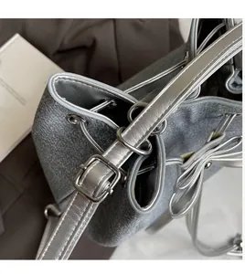 Detail of silver bucket bag showing smooth shoulder strap and metallic bow decoration