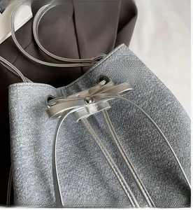 Detail of drawstring bucket bag with shiny metallic texture and bow decoration