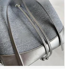 Detail of blue denim fabric and metallic silver leather strap on the large shoulder bag