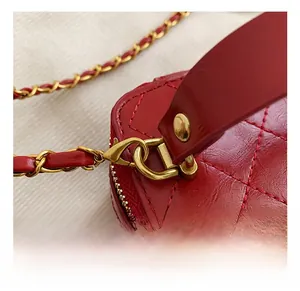 Macro shot of gold-tone metal hook and red quilted leather chain strap detail