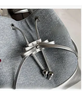 Detail shot of silver metallic textured bucket bag with drawstring and bow decoration