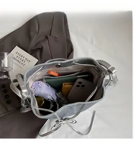 Spacious interior of silver drawstring bucket bag holding umbrella, wallet and phone