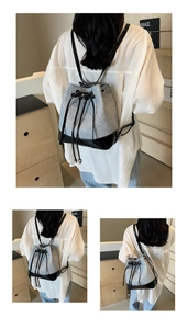 Detailed back view of a silver and black bucket backpack with drawstring and bow detail