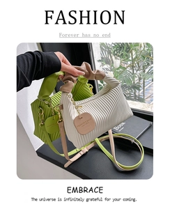 Detail of pleated shoulder bags in lime green and cream white with metal chain charm