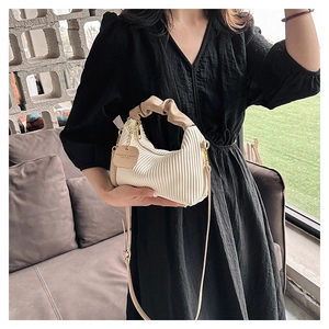 Détail du sac à main plissé blanc avec poignée chouchou kaki et étiquette en cuir