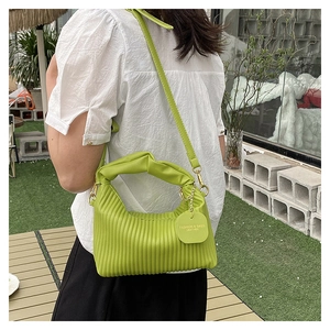 Détail du sac plissé vert avocat avec poignée torsadée et étiquette en cuir élégante