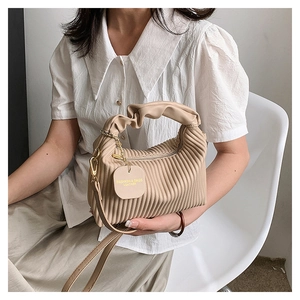 Gros plan du sac à main plissé beige avec textures verticales et chaîne dorée chic