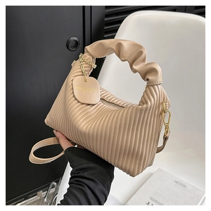 Détail du sac plissé couleur abricot avec poignée nuage et pendentif métallique