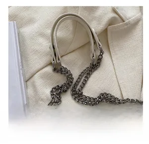 Close-up of white crocodile pattern shoulder strap with silver chain and leather handle