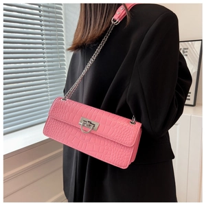 Pink croc-embossed small square bag with silver chain strap worn by a model