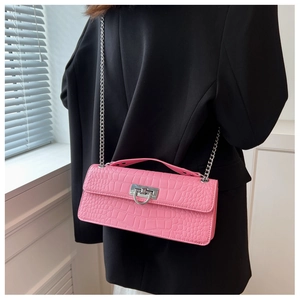 Detailed close-up of pink crocodile-textured baguette bag with silver chain on model