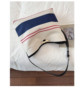 Detail of canvas beach tote with blue stripes, horn button closure and leather strap