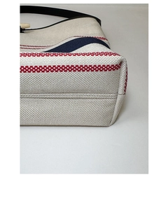 Detail of striped canvas tote bag showing bottom stitching and woven texture with horn buckle