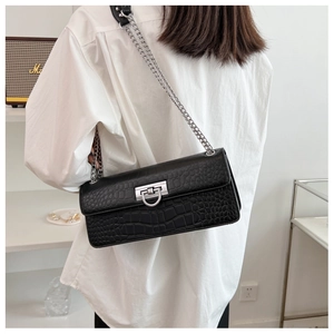 Detail of black faux leather baguette bag with crocodile pattern and silver chain strap