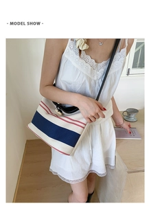 Detail of nautical striped canvas bucket bag with leather strap on a model's shoulder