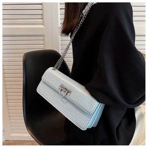 Detail of light blue crocodile pattern faux leather handbag with silver buckle closure