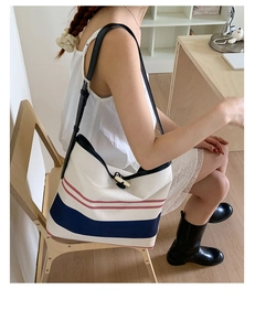 Detail of canvas tote with blue stripes, leather straps, and toggle horn button closure