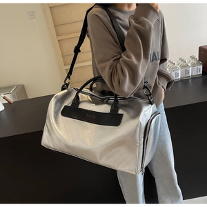 Bolsa de viaje plateada metálica con textura, asas negras y correa de hombro