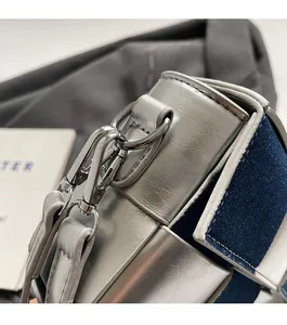 Detail of silver metallic hardware and blue denim stitching on luxury crossbody bag