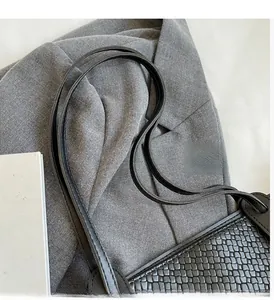 Close-up of black woven PU leather handbag with durable dual flat handle straps