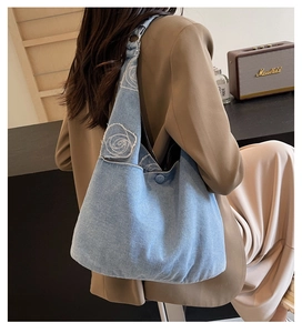 Detail of blue denim hobo bag featuring white rose embroidery and adjustable metal buckle