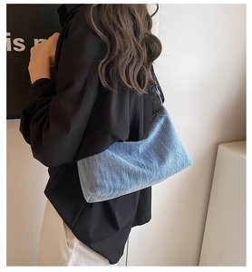 Side view of a light blue denim hobo bag worn as a shoulder bag on a model