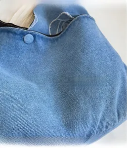 Macro shot of light blue denim handbag fabric with decorative buckle and white stitching