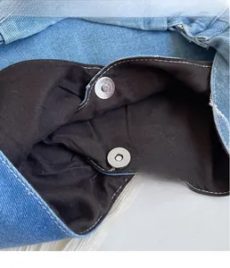 Detail view of denim handbag closure featuring durable round metal magnetic buckles