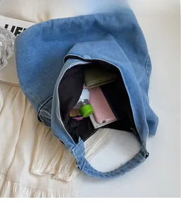 Interior view showing the spacious capacity of this blue denim tote with items and snap