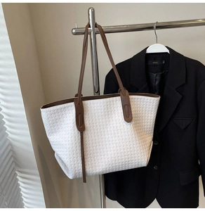 Close-up of white woven tote bag with contrast brown shoulder straps and leather texture