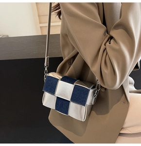 Detail of blue denim and silver woven checkerboard crossbody bag with metallic strap buckles