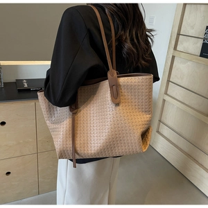 Detail of woven texture and leather straps on a khaki tote bag shown on model