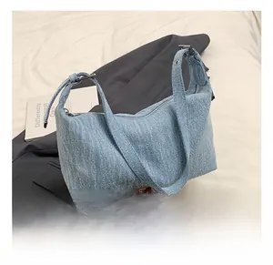 Close-up of light blue washed denim hobo bag with adjustable silver metal buckle strap