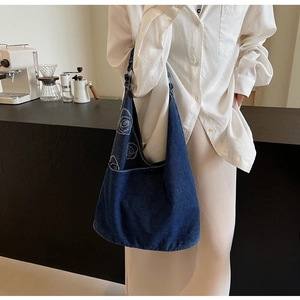 Détail d'un sac en denim avec motif de rose porté à l'épaule dans un décor de café