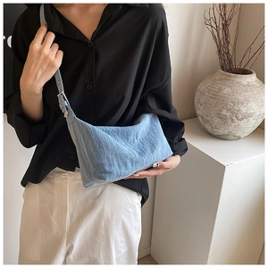 Detailed look at light blue denim shoulder bag styled with minimalist interior decor