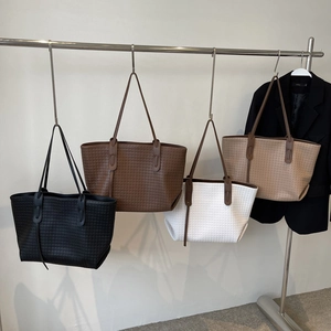 Minimalist woven tote bags in four colors displayed on a modern metal clothing rack