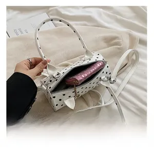 Spacious interior of white polka dot Boston bag showing a pink metallic wallet