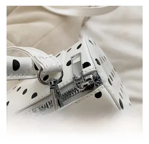 Close-up of silver metal zipper and D-ring on polka dot patent leather handbag