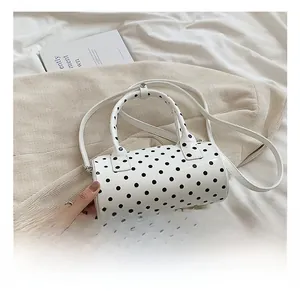 Close-up of a glossy polka dot Boston bag featuring black dots on white patent leather