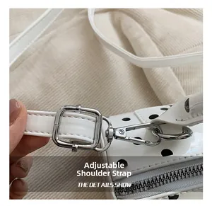 Close-up of adjustable strap with silver buckle on a white polka dot patent leather bag
