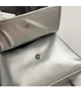 Dettaglio della borsa metallizzata argento con chiusura magnetica e texture in ecopelle