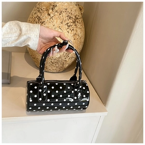 Detailed shot of a stylish black polka dot barrel bag with polished PU leather finish